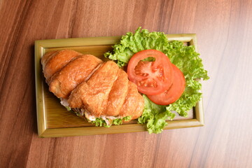 fried chicken or tuna fish with sesame sauce in baked crispy croissant bread and vegetables salad on wood table fresh halal pastry sandwich menu