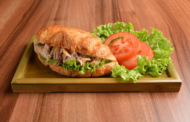 fried chicken or tuna fish with sesame sauce in baked crispy croissant bread and vegetables salad on wood table fresh halal pastry sandwich menu