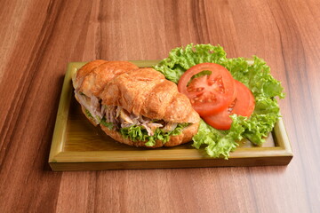 fried chicken or tuna fish with sesame sauce in baked crispy croissant bread and vegetables salad on wood table fresh halal pastry sandwich menu