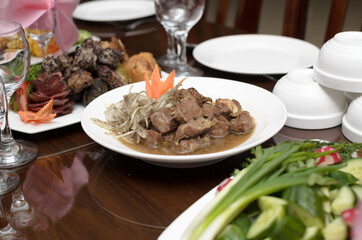 Slices of delicious stewed lamb meat with onions and gravy on a white plate on the banquet table