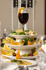 Glass of red wine with a slice of orange on a plate with fruit, bananas, kiwi, pear, apple, orange, lemon on the banquet table
