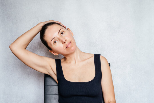 A woman gently pulls her head while doing the McKenzie method exercise for the neck, neck pain relief exercises