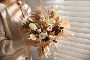 Woman holding beautiful dried flower bouquet near window at home, closeup - Powered by Adobe