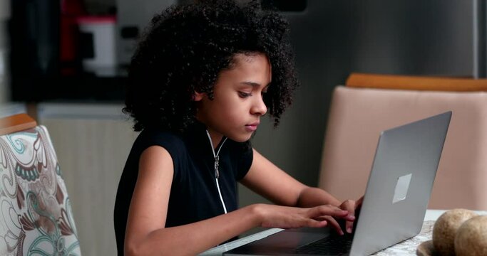 Candid black teen girl using laptop computer studying