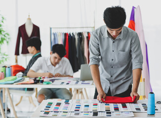 Asian tailor comparing cloth with samples