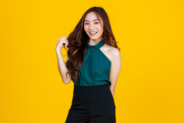 30s cute and charming curly hair Asian female brunette pose to camera with a joyful and positive gesture for advertising use purpose. Taken with studio flash isolated on yellow background