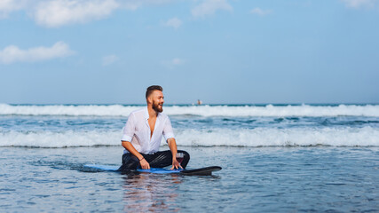 Fototapeta premium .European man drinking wine while sitting on a surfboard.