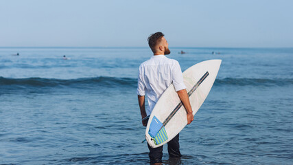 .European man with surfboard on the beach in the morning.