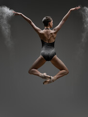 Fototapeta na wymiar Backview shot of jumping ballerina with outstretched arms