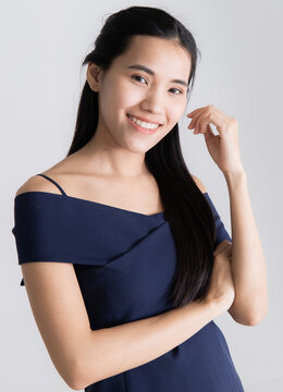 Image of portrait. Asian woman wearing a blue dress and smiling poses before taking a picture with a LED light in a white room at the studio. Concept model posing in studio.