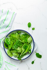 Organic raw spinach in bowl on white background
