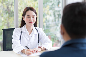 Asian professional  woman doctor who wears medical coat talks with a man patient to consult and suggest healthcare information to him.