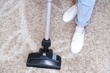 cordless vacuum cleaner is used to clean the carpet in the room. Housework with a new handheld vacuum cleaner.