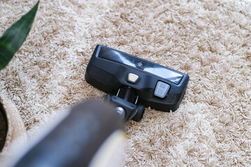 cordless vacuum cleaner is used to clean the carpet in the room. Housework with a new handheld vacuum cleaner.