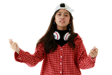 Determined Asian female in cool outfit and with headphones on neck looking at camera in studio on white isolated background Young