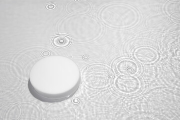 Empty white circle podium on transparent clear calm water texture with splashes and waves in sunlight. Abstract nature background for product presentation. Flat lay cosmetic mockup, copy space.