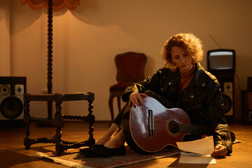 Woman playing acoustic guitar in a retro vintage room.