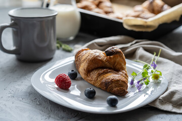 breakfast concept with just made fresh croissants and milk on the grey table