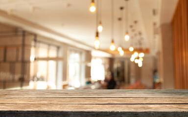 image of wooden table in front of abstract blurred background cafe restaurant bar recreates bokeh lights. With big blurry windows