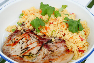 close up of Couscous mediteranean food with vegetable served with piece of grilled pork, isolated on white background.