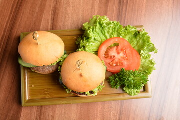 two baked mini chicken / pork / beef meat burger bun and vegetables salad on wood table fresh halal pastry sandwich menu