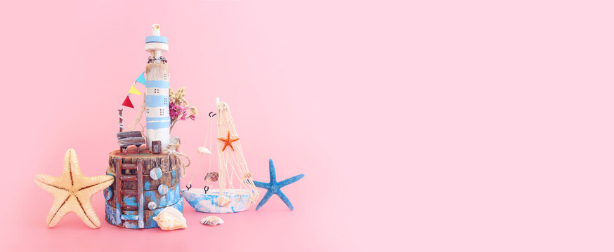 Nautical concept with sea life style objects as boat, driftwood beach house, seashells and starfish over pink pastel background