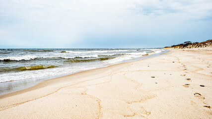 Sea waves and footprints on the sand on the beach and overcast sky