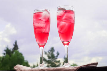 Two glasses of red summer cocktail with ice outdoors
