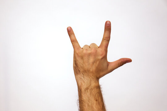 Hand on white shows rock and roll gesture. Caucasian man raised his hand in air