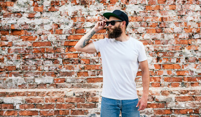 Young bearded hipster guy wearing white blank t-shirt. Mock-up for print. T-shirt template.