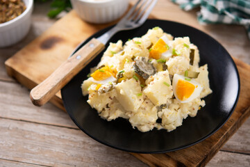 Potato salad with gherkins, egg and mustard on wooden table