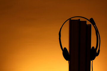 Abstract Book with earphone. E book, Audio Book. Shoot in orange color background. With a grow light behind the book. Lifestyle concept. 