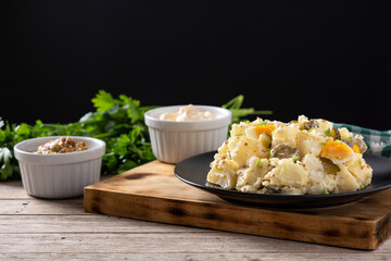 Potato salad with gherkins, egg and mustard on wooden table. Copy space