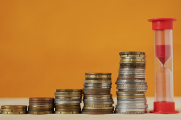 The pyramid of stacks of coins goes up, with an hourglass at the head