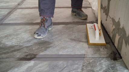 Laying floor tiles, tiler cleaning tiles after filling up joints. Cleaning tiles after laying on the floor.