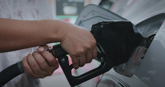Woman hand holding fuel nozzle and put in to automobiles tank