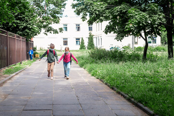 Fototapeta na wymiar Two girls running back to school and wearing mascks during coronavirus pandemic. Primary school