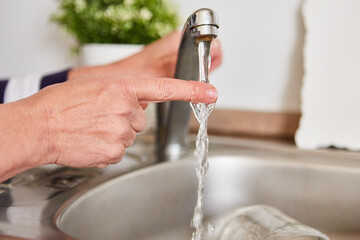 Finger unter dem fließenden Wasser am Wasserhahn