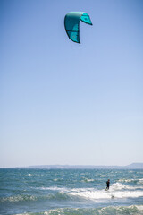 A kiteboarder is pulled across water by a power kite in strong onshore winds in Empuriabrava, Costa Brava, province of Girona, Catalonia, Spain. Kiteboarding, kitesurfing, extreme sport.