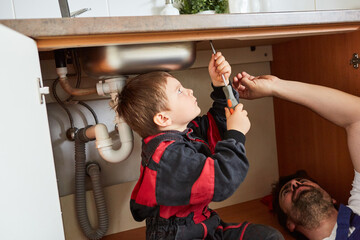 Kind mit Schraubenzieher bei Reparatur der Spüle