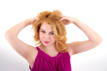 Fototapeta premium Beautiful female model with blonde long curly hair posing in studio on a white bacground in nice dress