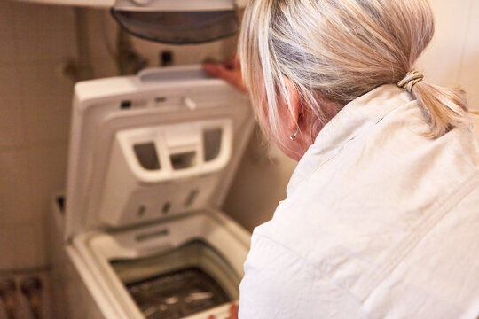 Hausfrau kontrolliert eine Toplader Waschmaschine