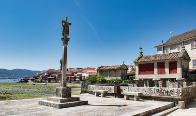 Fototapeta na wymiar Cruz de piedra y tradicionales hórreos gallegos en la hermosa villa medieval de Combarro, España