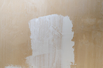 a thin layer of white putty on beige gypsum plaster