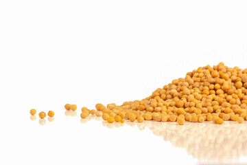 Heap of white mustard (Sinapis alba) seeds on white background, reflection, side view, superfood concept with copy space.