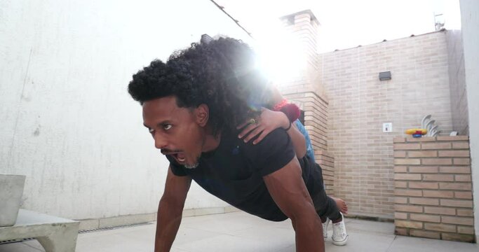 Father and daughter bonding together, child on dad back doing push-up