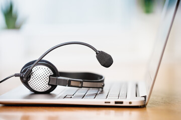 Laptop. Close up of headphones or headset on desk and plain background banner. Distant learning or working from home, online courses or customer support minimal concept. Helpdesk or call center - obrazy, fototapety, plakaty