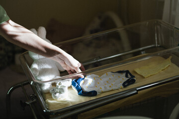 Maternal hand straightens clothes for a newborn 