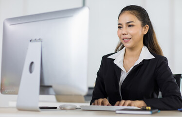 Focus to asian woman office people wearing suit sitting at working desk and using computer while smile with happy