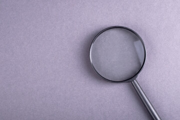 Concept of search and question with magnifying glass on gray bakcground
